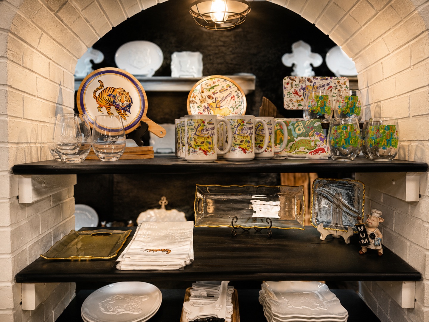 Louisiana tiger plates, hand-painted mugs, and glassware under the white brick arches at Bernard's
