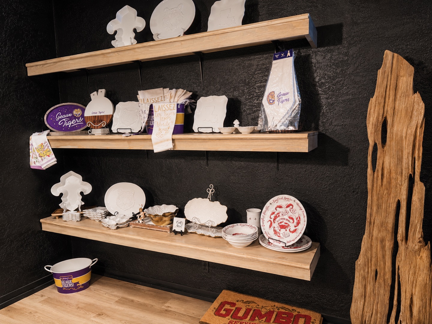 Geaux Tigers trays, tea towels, and Louisiana dishware on warm wood shelving at Bernard's